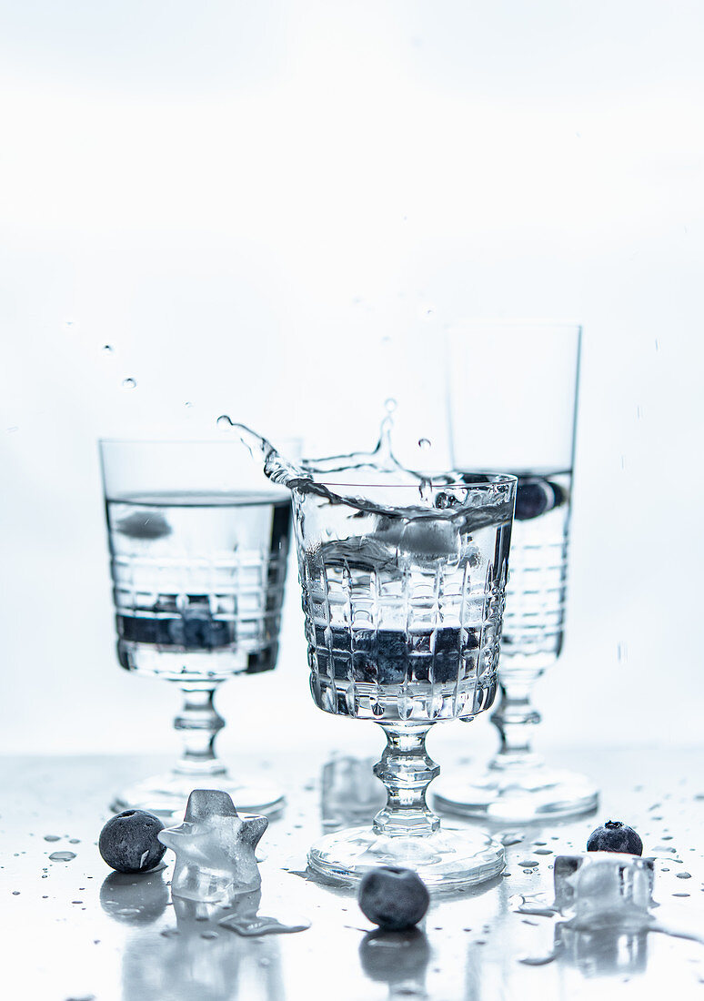 Stem glasses with splash of drink and blue berries