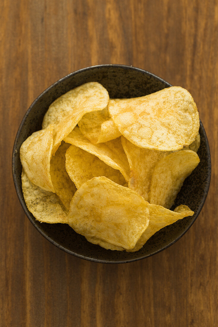 Crispy potato chips in a bowl (overhead shot)