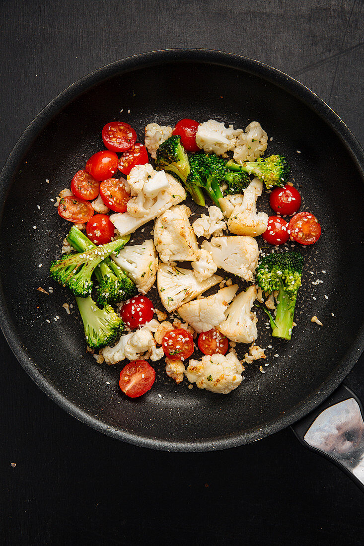 Tomatoes frying with cauliflower and broccoli