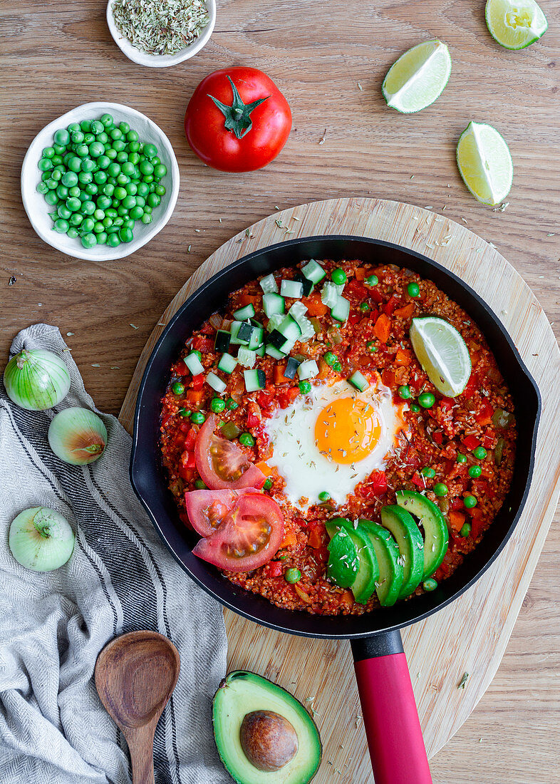 Shakshuka with eggs and quinoa placed on table with fresh ingredients