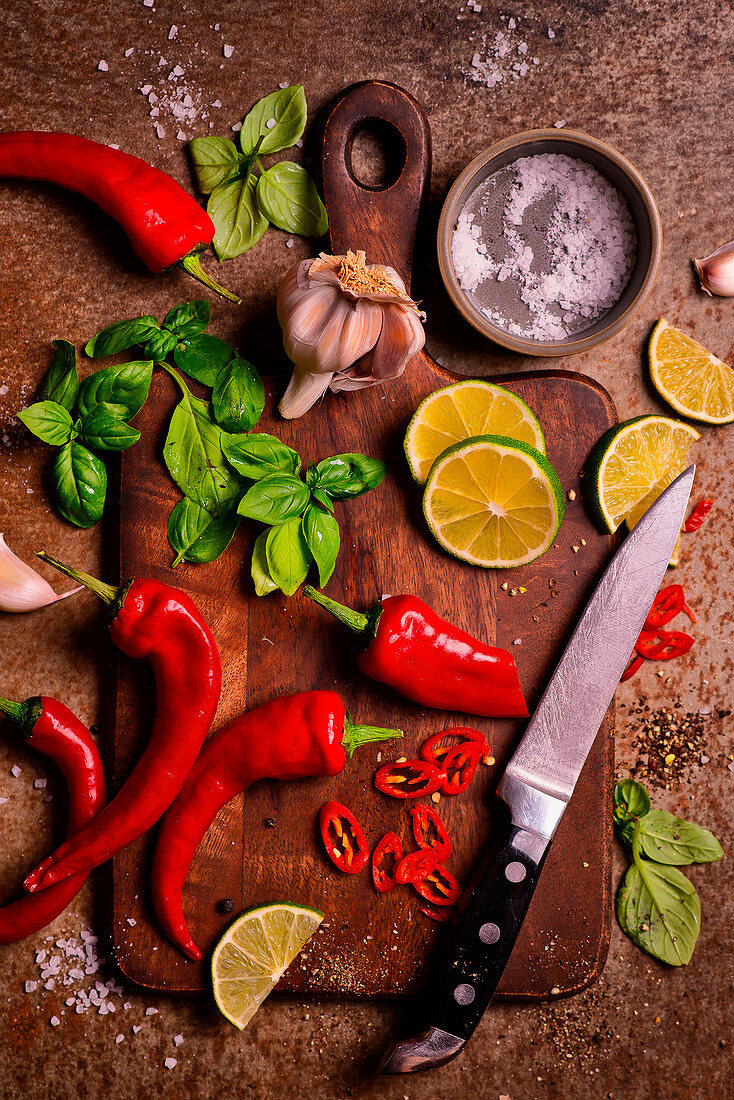 Chopping board with knife and chilli, basil, lime, garlic and salt