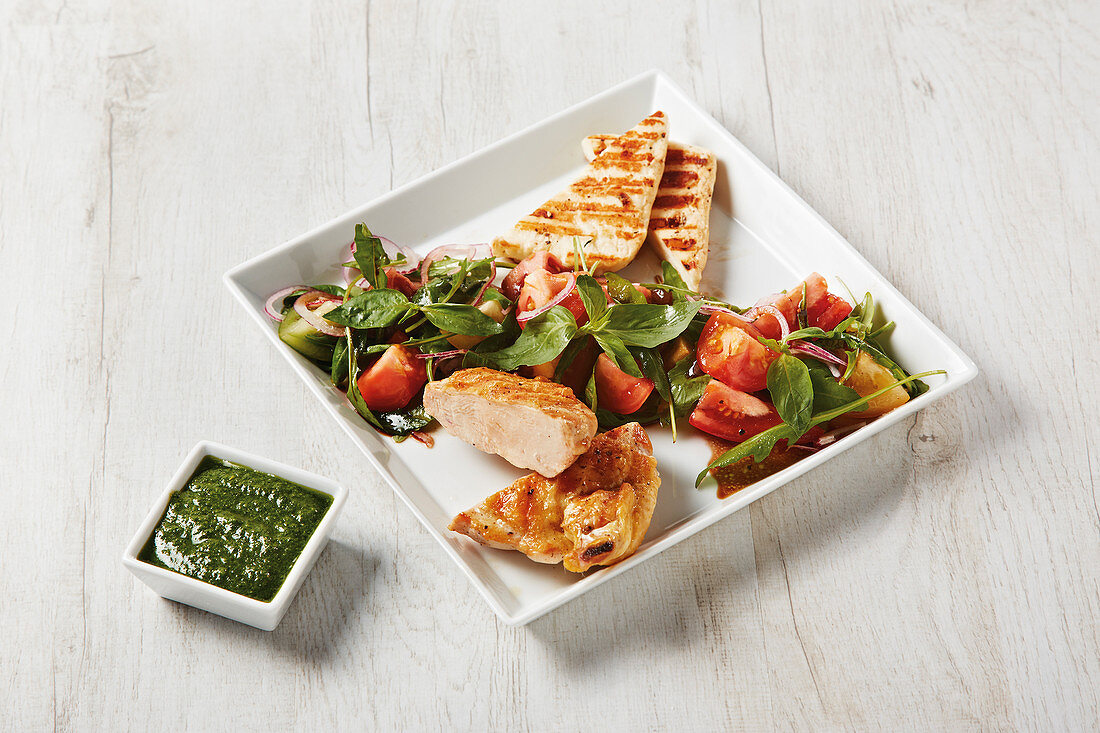 Grilled corn-fed chicken with halloumi, colourful tomato salad and pesto