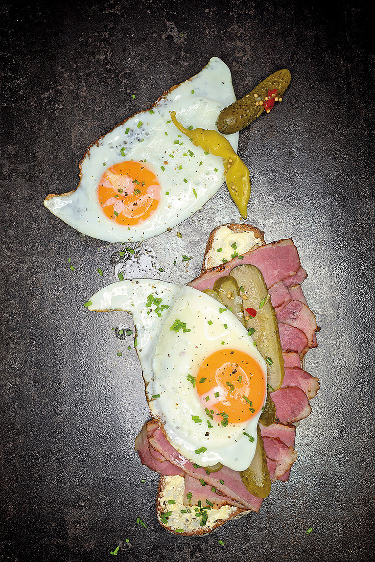 Grilled pastrami on bread with a fried egg and gherkins