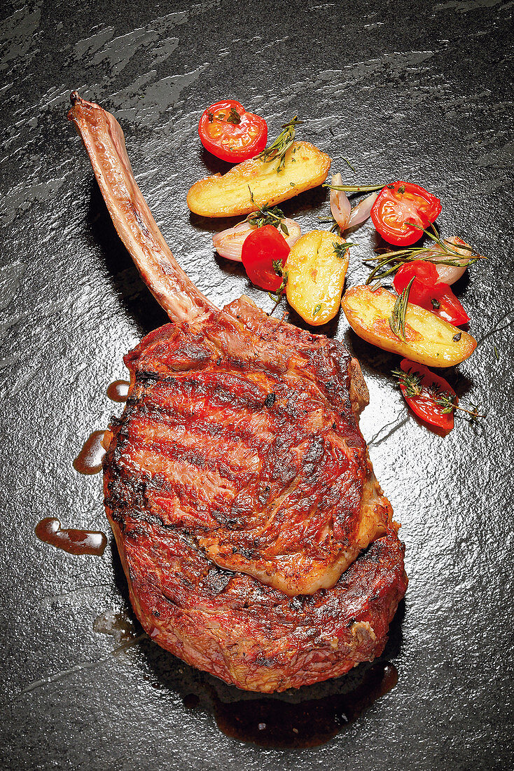 Grilled tomahawk steak with a potato and tomato ragout