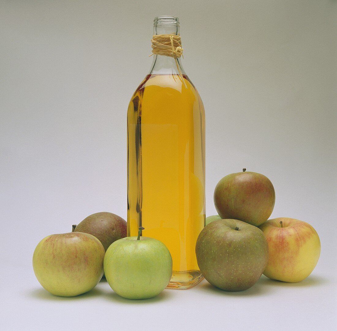 A bottle of cider vinegar, decoration: six fresh apples