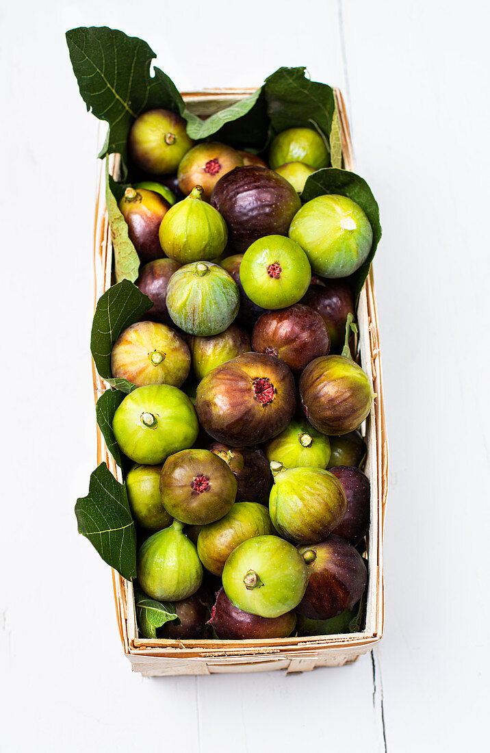 A wooden panier filled with freshly picked green and purple figs