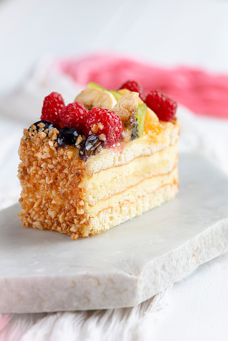 Classic vanilla and sponge fruit slice decorated with chopped nuts