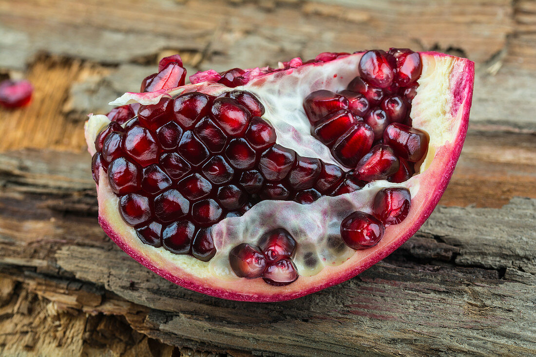 A piece of pomegranate on a wooden surface