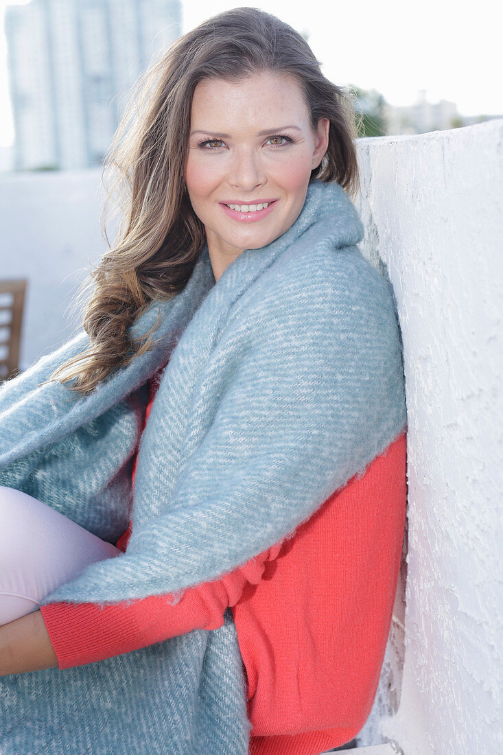 A young woman wearing a coral jumper with a shawl over her shoulders