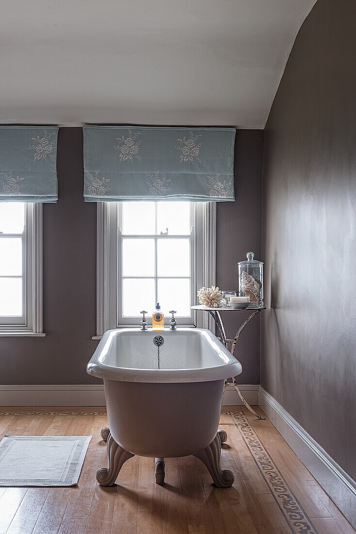 Freestanding bath with light blue emboidered curtains at window in restored 16th century farmhouse