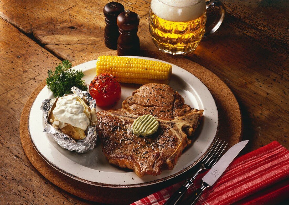 T-bone steak with corncobs, grilled tomatoes & baked potato