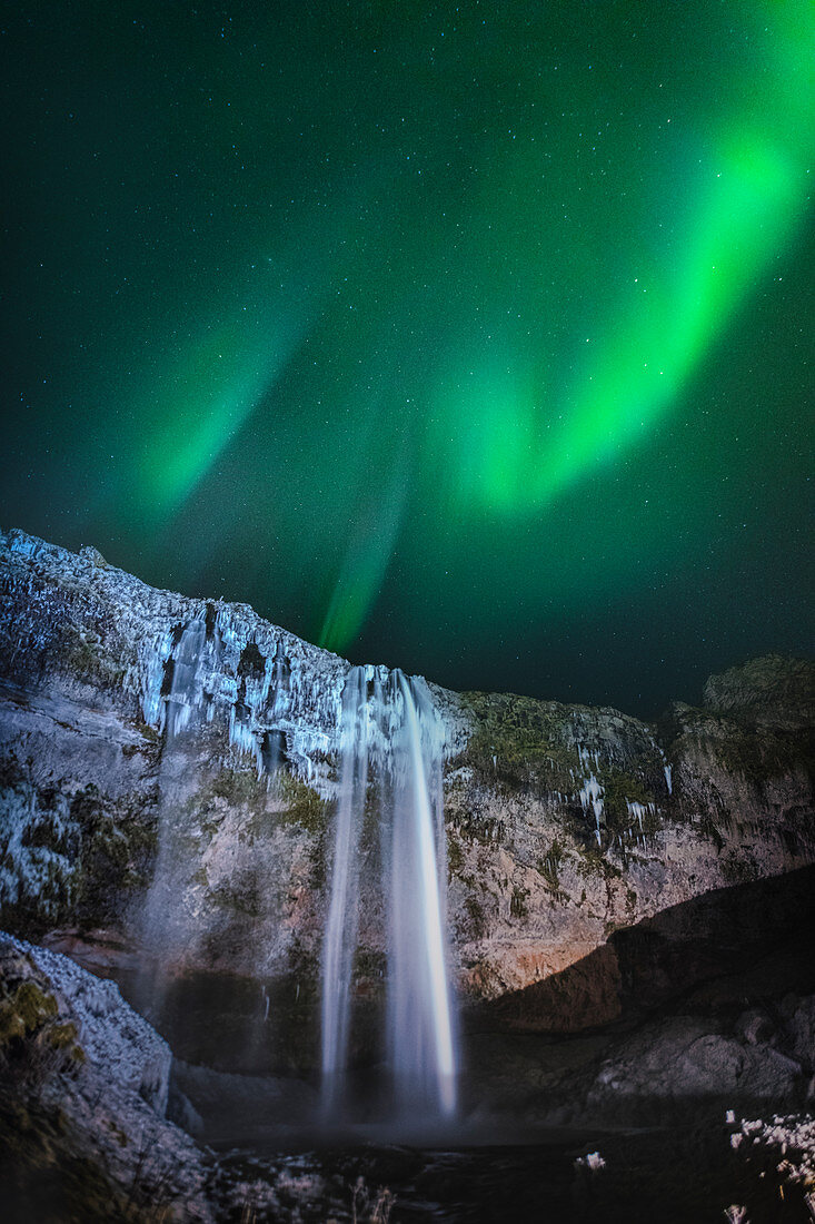 Aurora borealis over waterfall