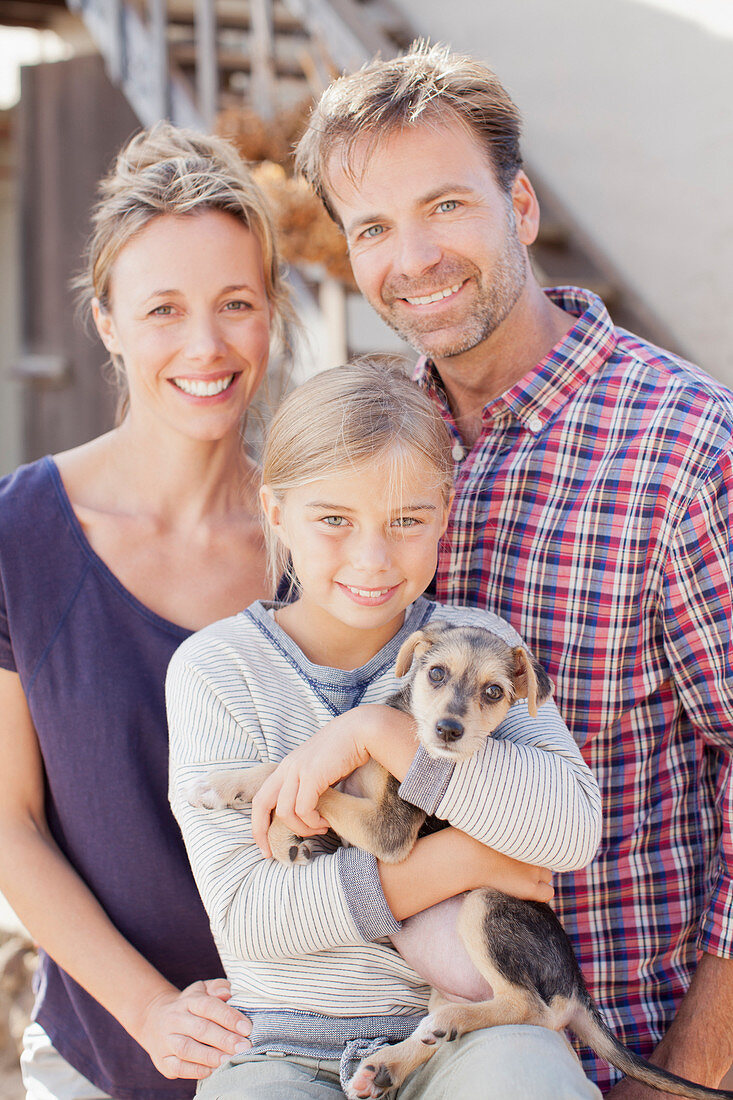 Portrait of smiling family holding puppy