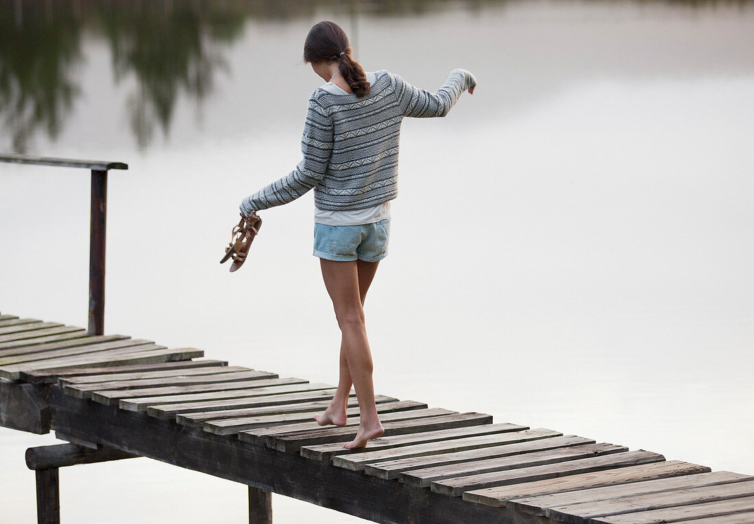 Woman walking along dock over lake