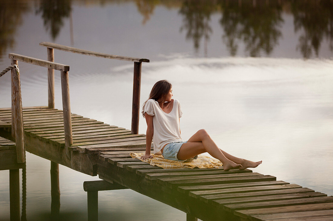 Woman sitting on dock over lake