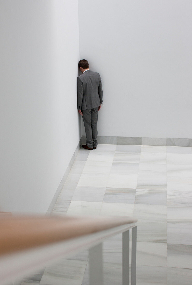Dejected businessman standing in corner