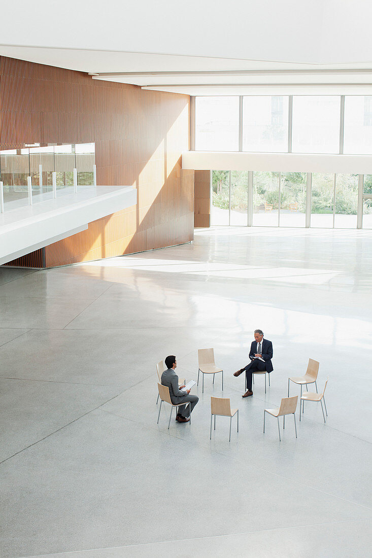 Businessmen sitting at circle of chairs