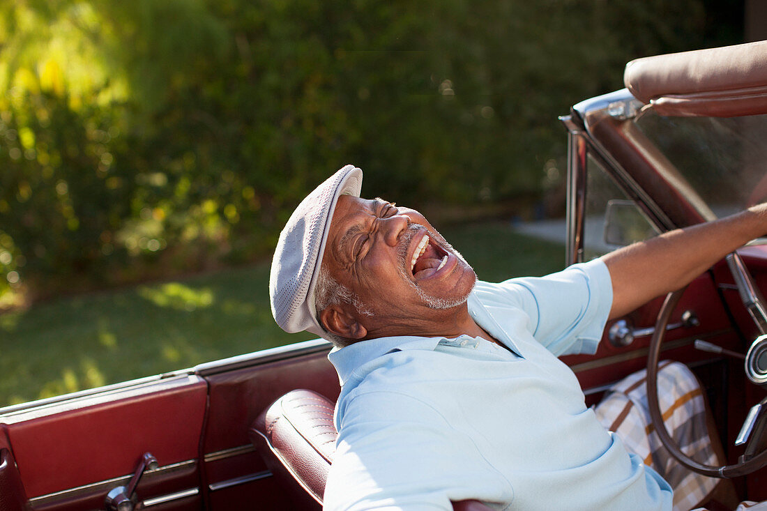 Laughing older man driving convertible