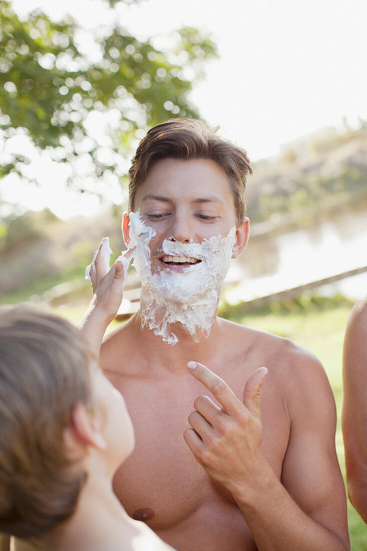 Son helping father apply shaving cream
