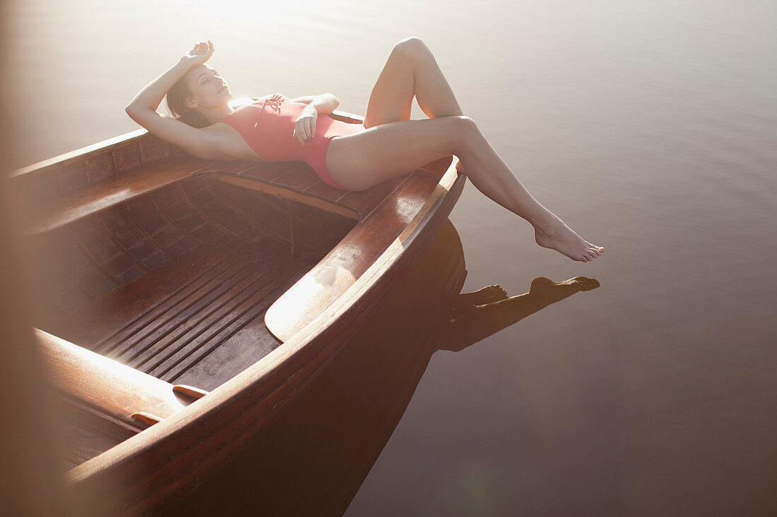 Serene woman sunbathing in boat on lake
