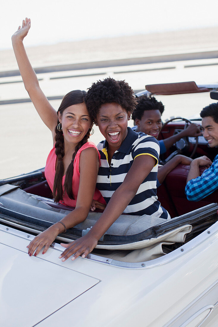 Smiling women cheering in convertible