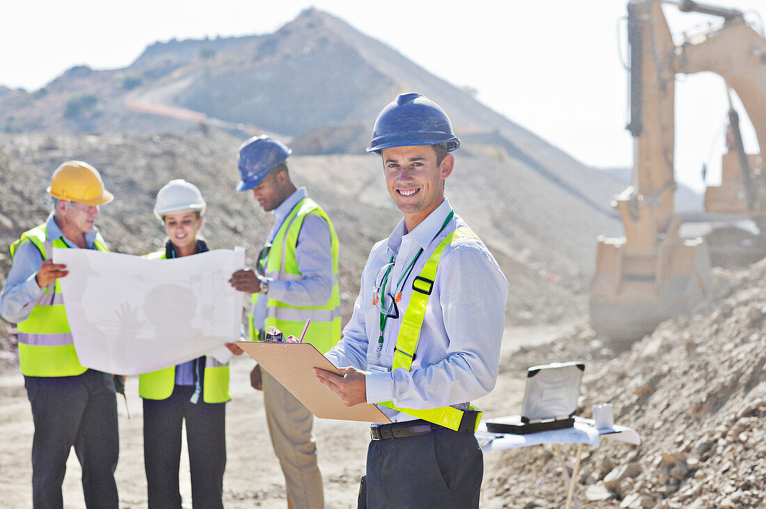 Businessmen reading blueprints in quarry