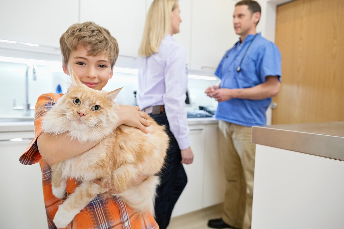 Owner holding cat in vet's surgery