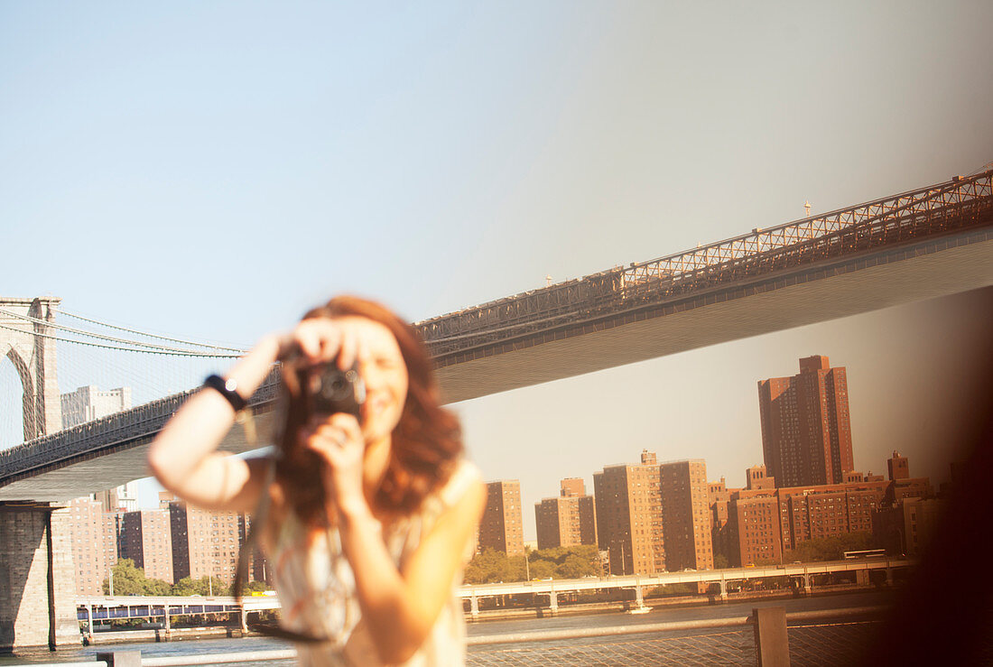 Woman taking pictures by urban bridge