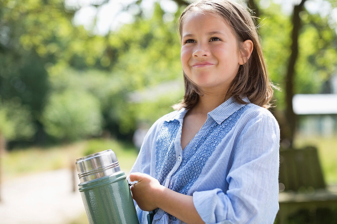 Girl carrying thermos outdoors
