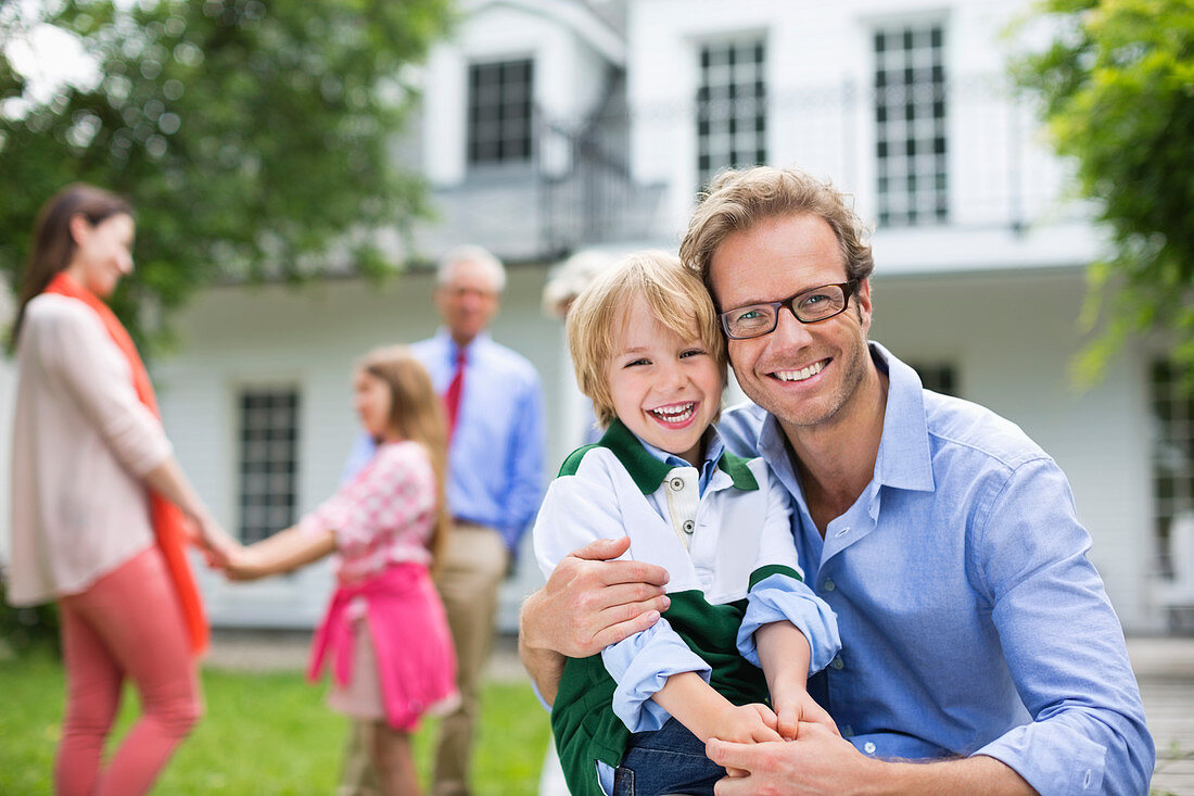 Father and son smiling outside house