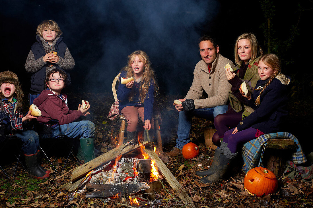 Family eating around campfire at night