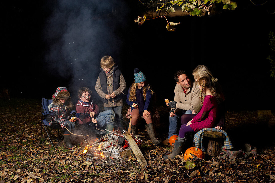 Family eating around campfire at night