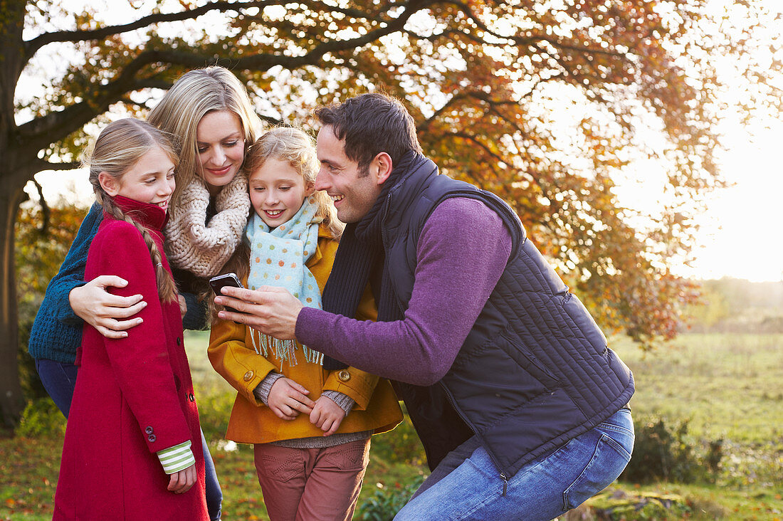 Family using cell phone together outdoors