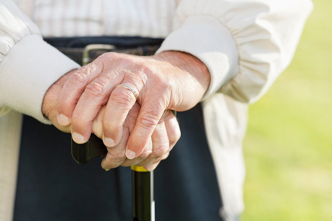 Close up of older man's hands on cane