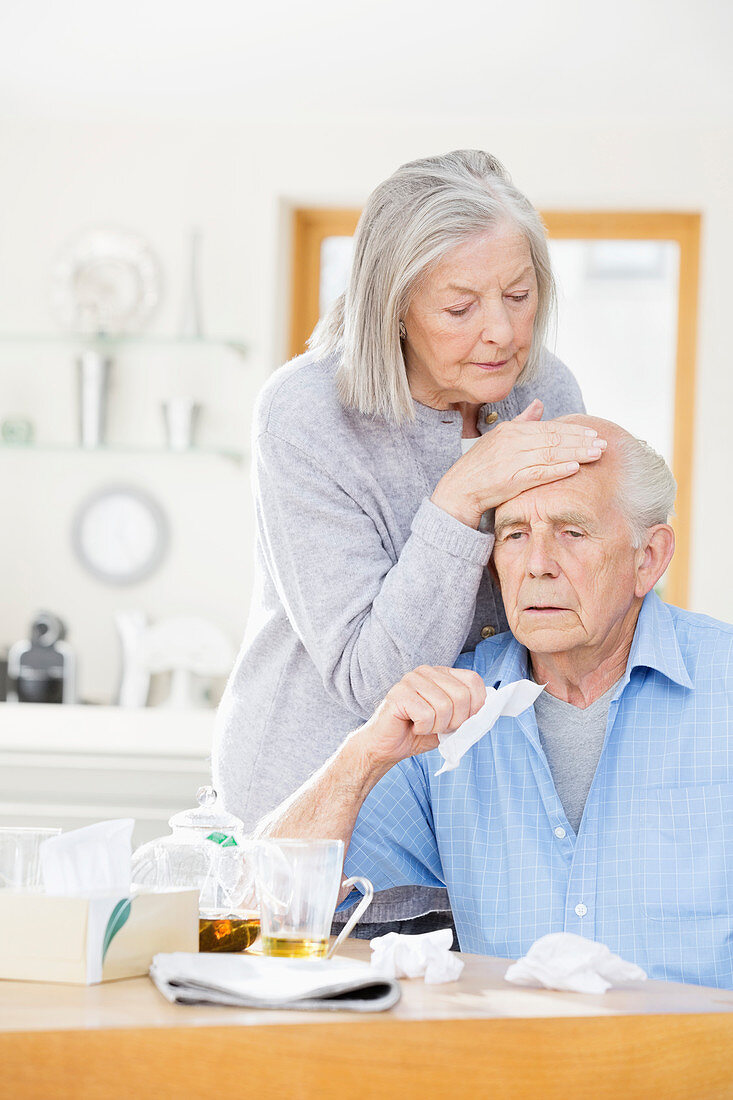 Woman feeling sick husband's forehead
