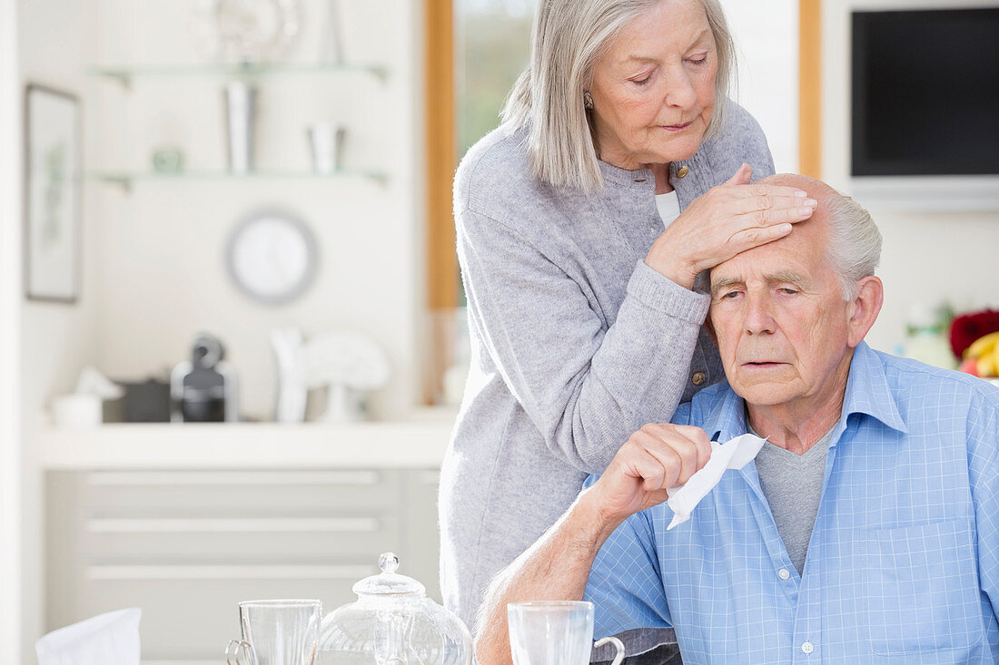 Woman feeling sick husband's forehead