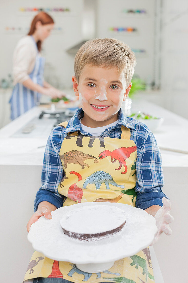 Boy covered in flour holding cake