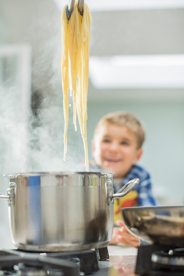 Boy watching parent cook spaghetti