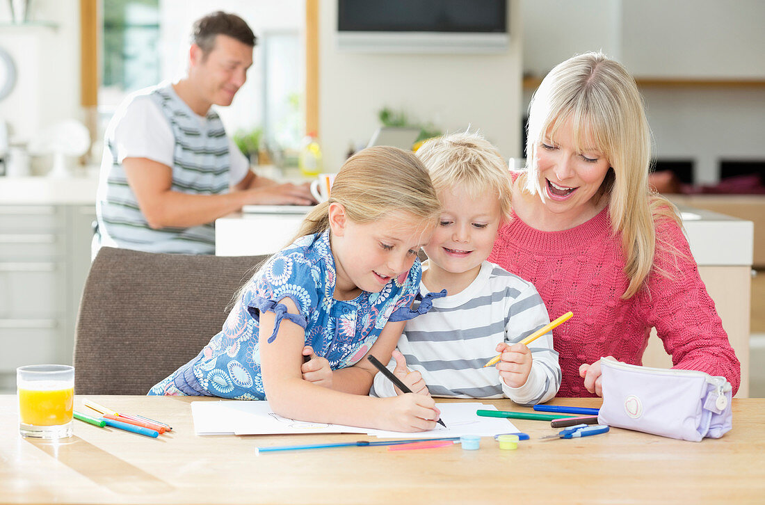 Mother and children coloring at table