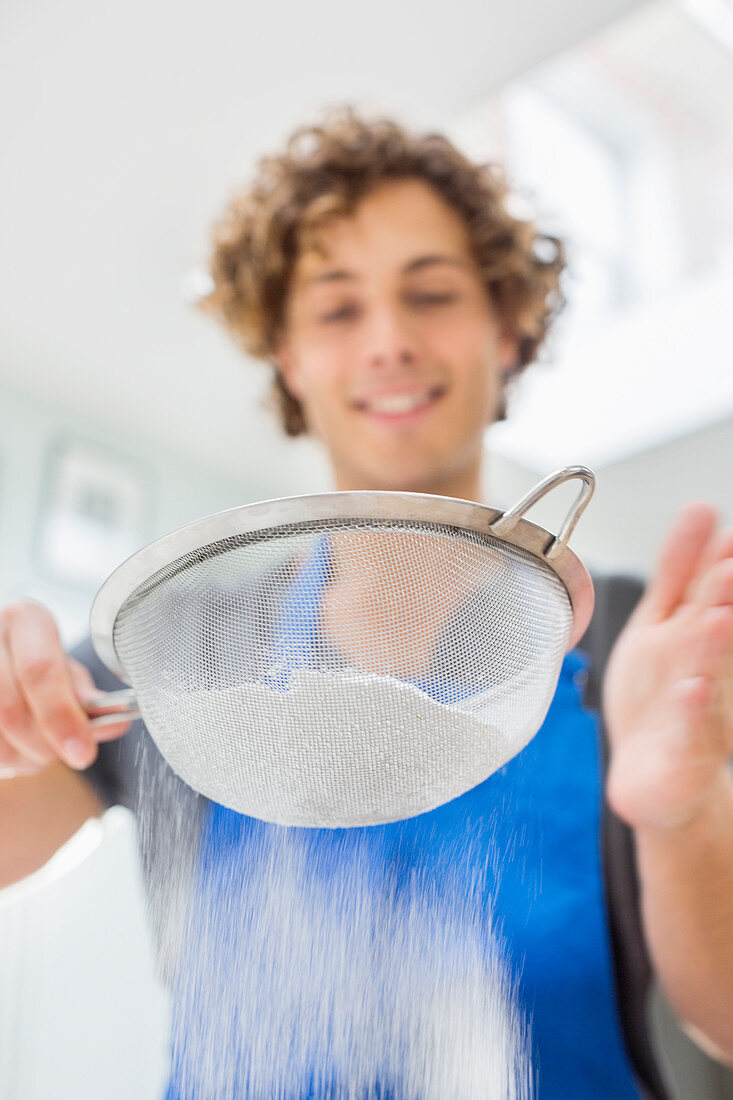 Man sifting flour in kitchen