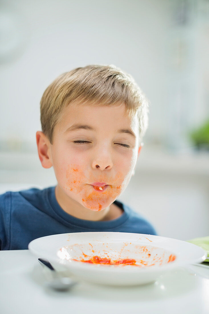 Boy slurping spaghetti at table