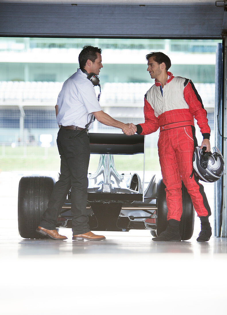 Racer and manager shaking hands in garage