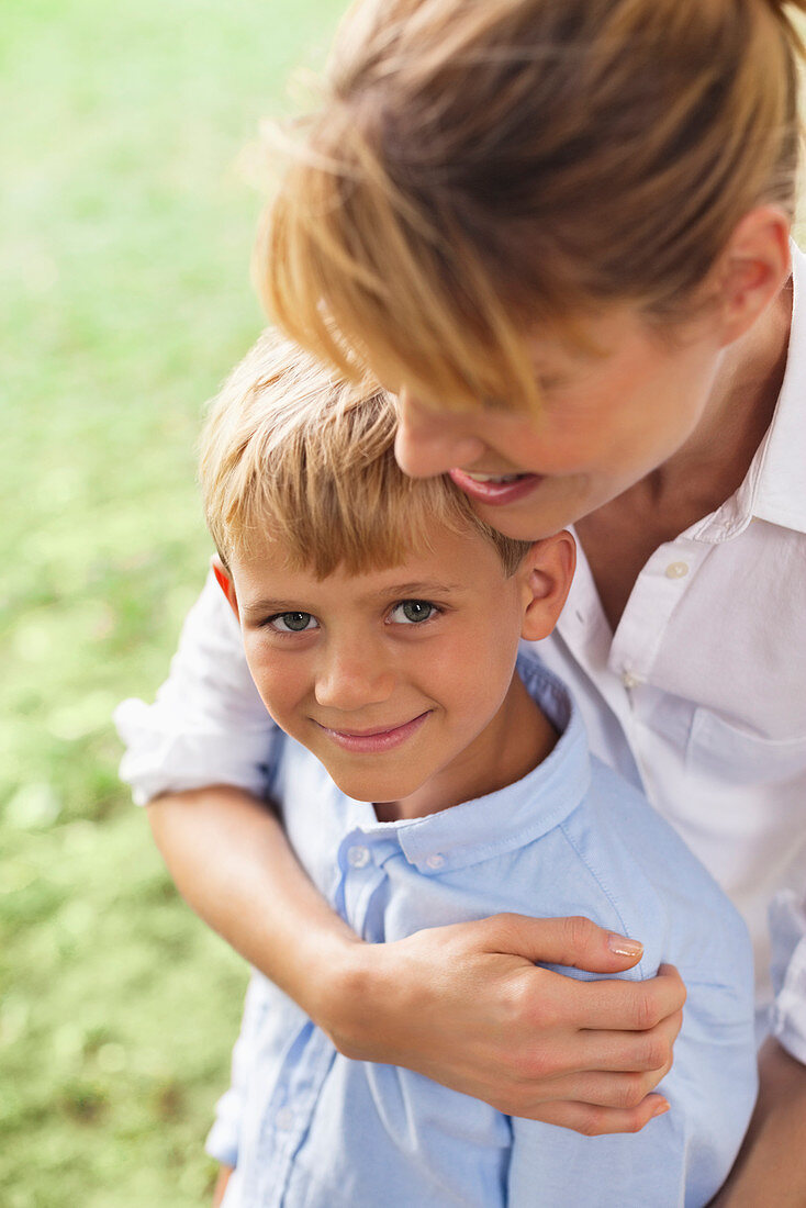 Mother hugging son in park