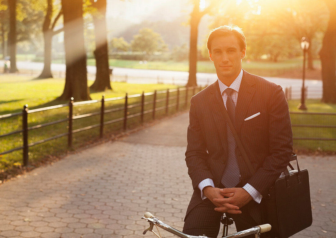 Businessman sitting on bicycle in park