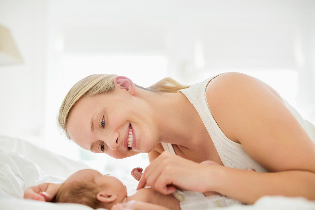 Mother cradling newborn infant on bed