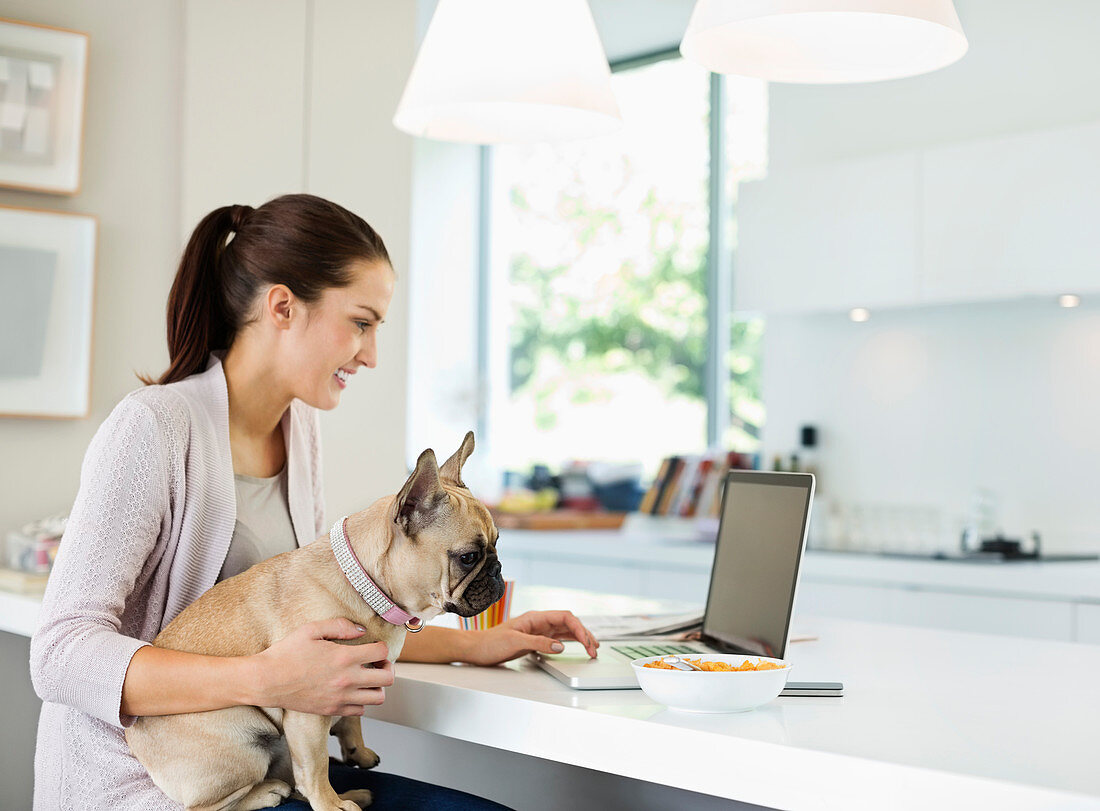 Woman using laptop with dog on lap