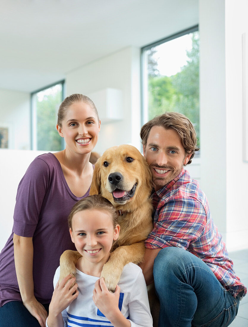 Family smiling with dog indoors