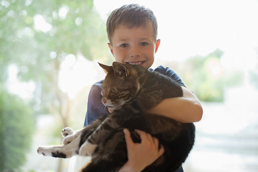 Smiling boy holding cat indoors