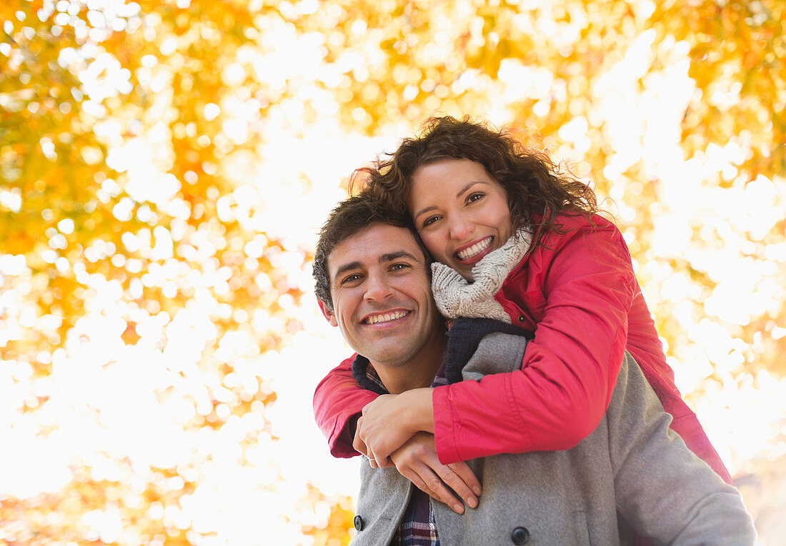 Man carrying girlfriend piggyback in park