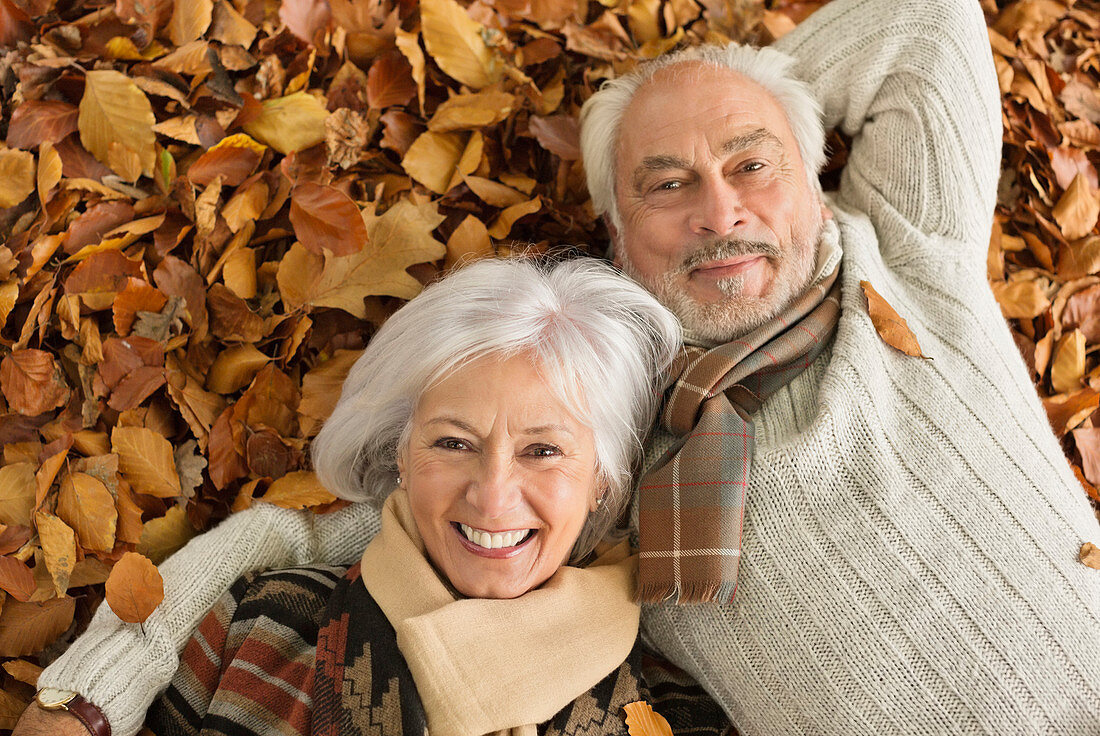 Older couple laying in autumn leaves